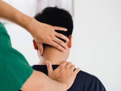 physiotherapist massage therapist holding male client's head and massaging tight neck muscles the result of prolonged use of mobile phones.Office Syndrome